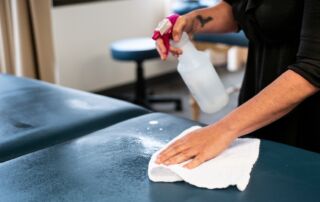 massage therapist cleaning up table to prevent fungal disease